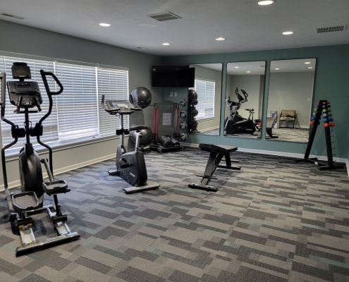 Fitness center with a bench and cardio equipment at Lynhurst Park Apartments